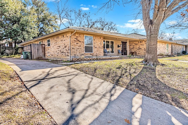 ranch-style house with brick siding, a porch, and fence