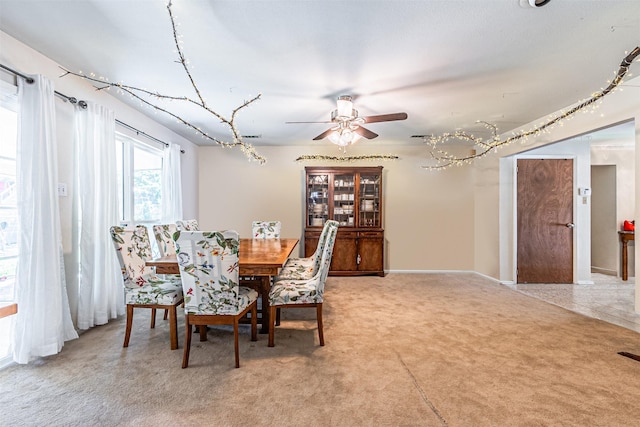 dining area with light carpet, ceiling fan, and baseboards