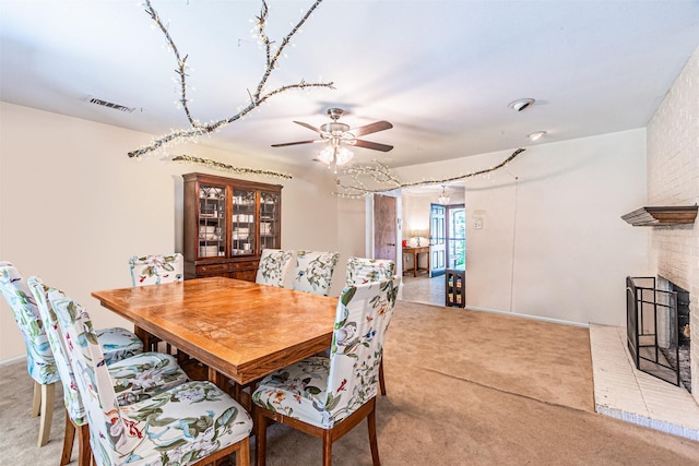 carpeted dining area featuring ceiling fan and a fireplace