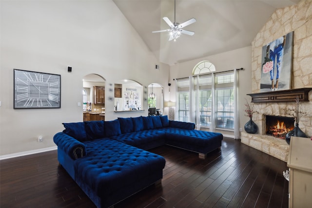 living room featuring high vaulted ceiling, a fireplace, ceiling fan, and dark hardwood / wood-style flooring