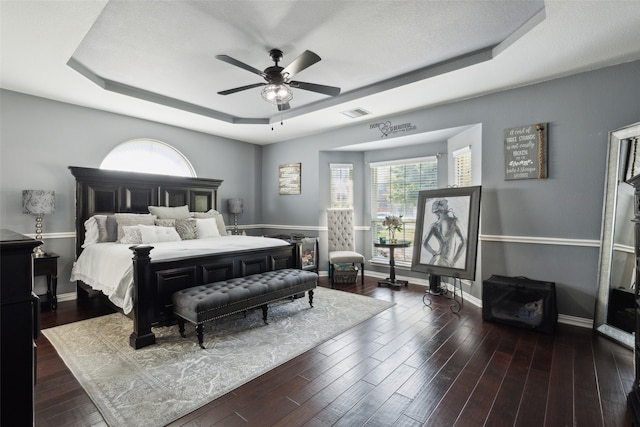 bedroom with ceiling fan, a raised ceiling, and dark hardwood / wood-style floors