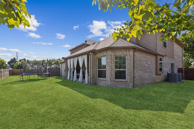 view of side of home featuring a yard, central AC, and a trampoline