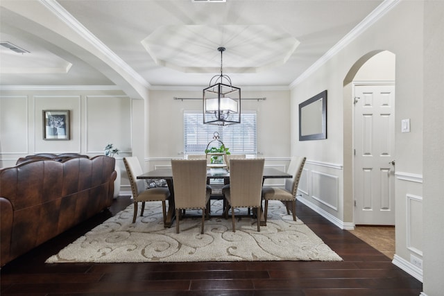 dining area featuring dark hardwood / wood-style floors, a tray ceiling, an inviting chandelier, and ornamental molding