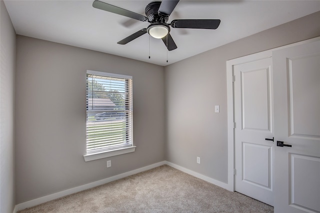 unfurnished bedroom with a closet, light colored carpet, and ceiling fan