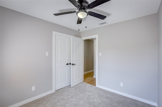 unfurnished bedroom with ceiling fan, light colored carpet, and a closet