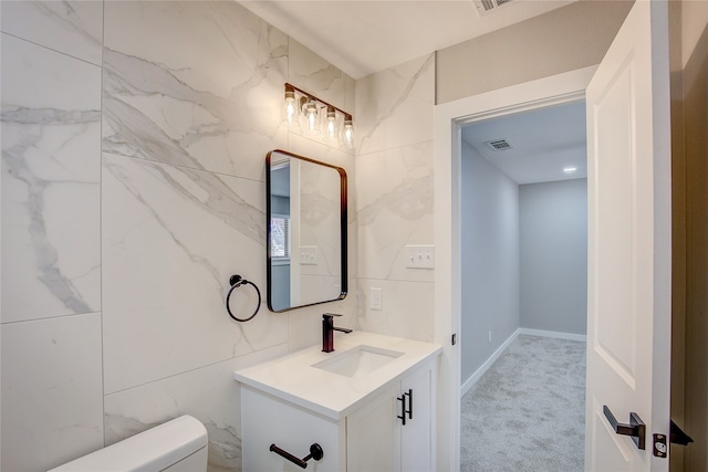 bathroom featuring vanity, toilet, and tile walls