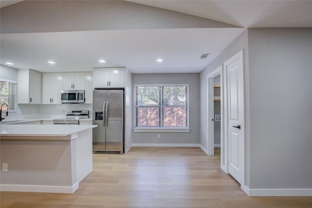 kitchen featuring backsplash, white cabinets, sink, light wood-type flooring, and stainless steel appliances