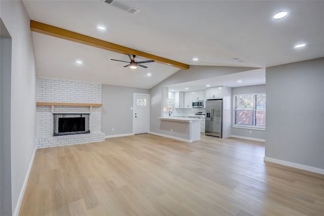 unfurnished living room with ceiling fan, sink, a brick fireplace, vaulted ceiling with beams, and light wood-type flooring