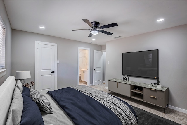 carpeted bedroom with ensuite bathroom and ceiling fan