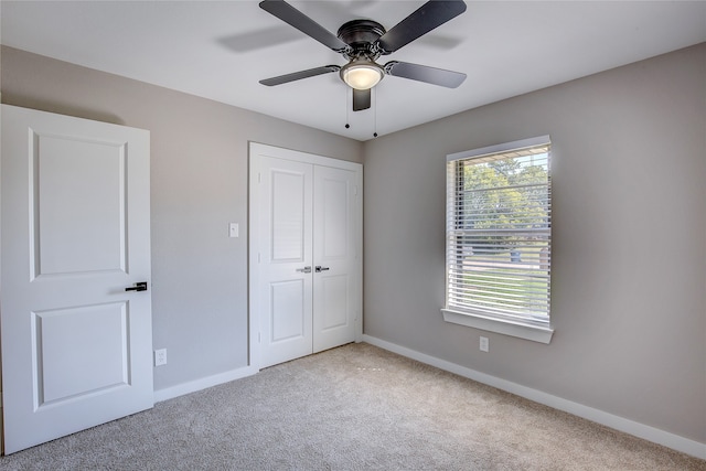 unfurnished bedroom with light carpet, a closet, and ceiling fan