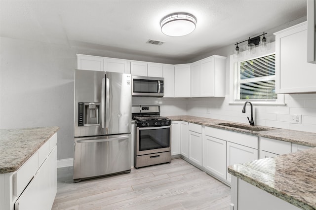 kitchen featuring light stone countertops, appliances with stainless steel finishes, sink, and white cabinetry