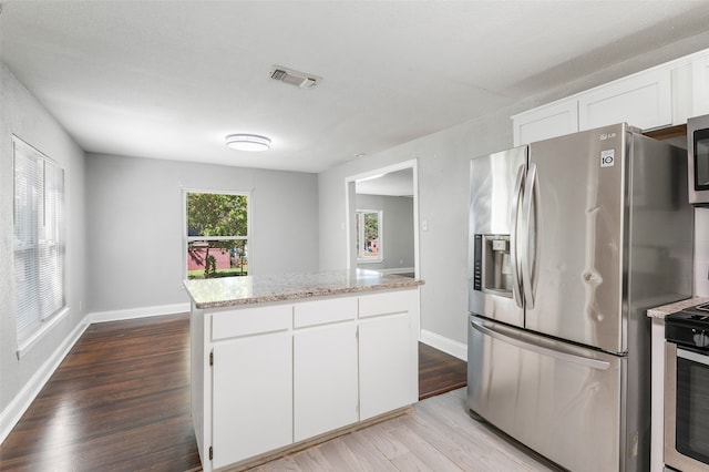 kitchen featuring light stone counters, light hardwood / wood-style floors, white cabinetry, a kitchen island, and appliances with stainless steel finishes