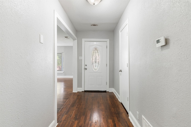 doorway featuring a textured ceiling and dark hardwood / wood-style flooring