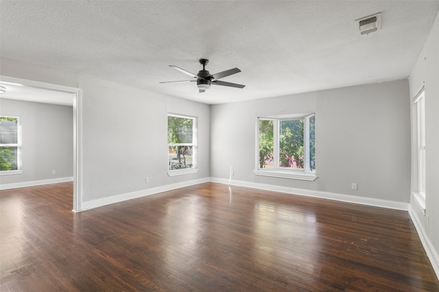 unfurnished room featuring a wealth of natural light, ceiling fan, dark hardwood / wood-style floors, and a textured ceiling