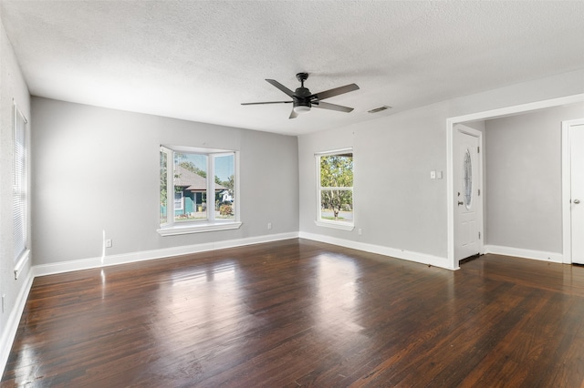 empty room featuring ceiling fan, a textured ceiling, plenty of natural light, and dark hardwood / wood-style floors