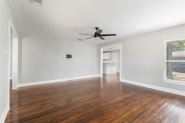 empty room featuring a textured ceiling, ceiling fan, and dark wood-type flooring