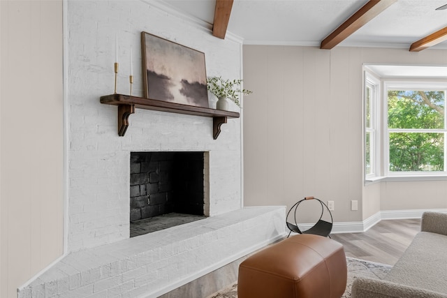 living room featuring beam ceiling, light hardwood / wood-style floors, and a brick fireplace