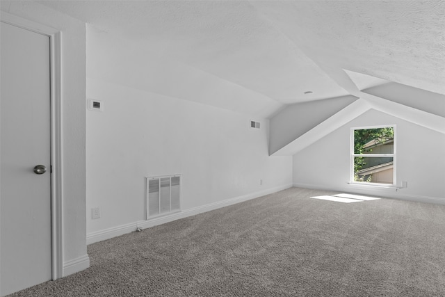 bonus room with vaulted ceiling, carpet floors, and a textured ceiling