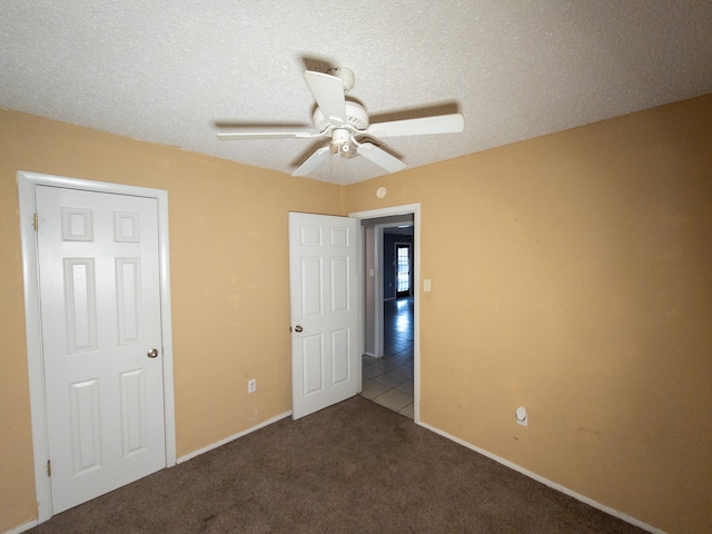 unfurnished bedroom featuring ceiling fan, carpet floors, and a textured ceiling