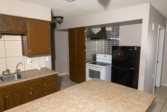 kitchen with sink, wall chimney exhaust hood, decorative backsplash, black refrigerator, and white range with electric cooktop