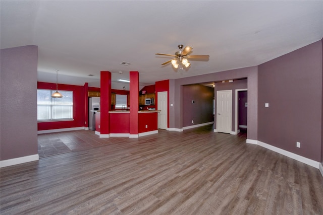 unfurnished living room with ceiling fan and dark wood-type flooring