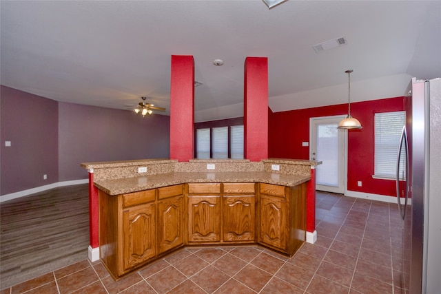 kitchen featuring dark tile patterned flooring, light stone counters, stainless steel refrigerator, decorative light fixtures, and ceiling fan