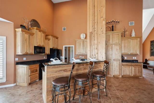 kitchen with light brown cabinets, black appliances, and a high ceiling