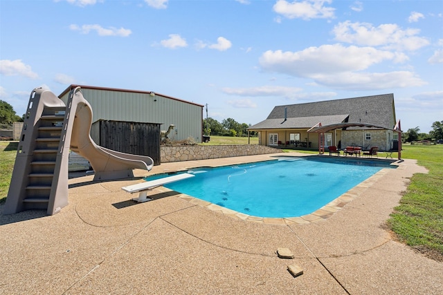 view of swimming pool with a diving board, a patio area, and a water slide