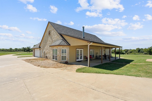 view of side of property with french doors, a yard, a garage, and a patio area