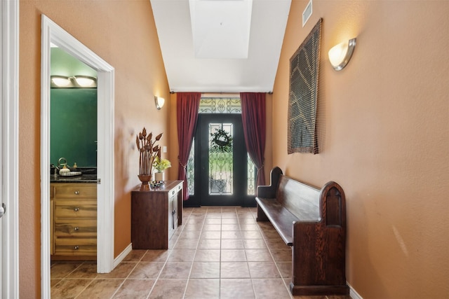 entrance foyer with light tile patterned flooring and vaulted ceiling