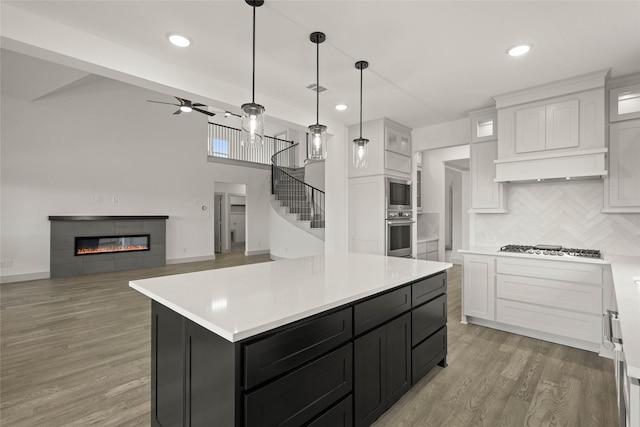 kitchen featuring a center island, light countertops, glass insert cabinets, white cabinets, and dark cabinets