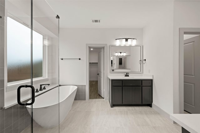 full bathroom with a soaking tub, a spacious closet, visible vents, and vanity