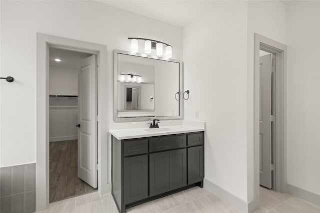 full bath featuring baseboards, a spacious closet, vanity, and tile patterned floors