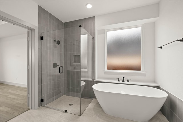 bathroom featuring a stall shower and a soaking tub