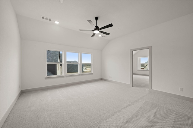 unfurnished room with visible vents, vaulted ceiling, light carpet, and baseboards