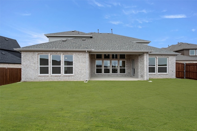 rear view of property with a patio area, a fenced backyard, roof with shingles, and brick siding