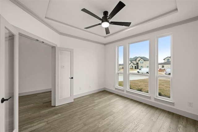 unfurnished bedroom with baseboards, a raised ceiling, and wood finished floors