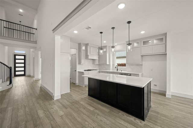 kitchen featuring glass insert cabinets, light countertops, a kitchen island, and white cabinetry