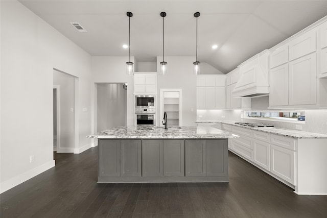 kitchen featuring white cabinets, appliances with stainless steel finishes, and an island with sink