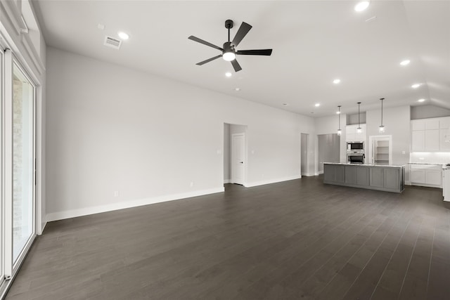 unfurnished living room with a healthy amount of sunlight, ceiling fan, and dark hardwood / wood-style flooring