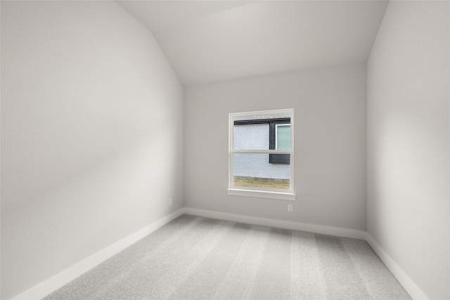 empty room featuring carpet and vaulted ceiling