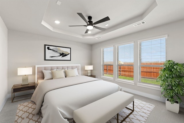 carpeted bedroom featuring ceiling fan and a raised ceiling