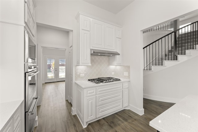 kitchen featuring french doors, tasteful backsplash, stainless steel appliances, dark wood-type flooring, and white cabinetry