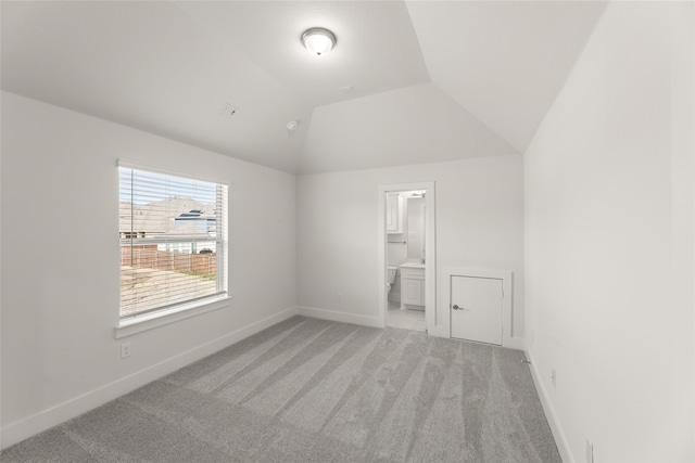 carpeted empty room featuring vaulted ceiling