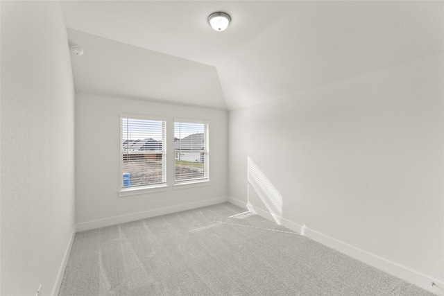 carpeted empty room with lofted ceiling