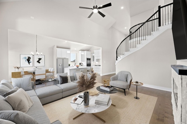 living room featuring ceiling fan with notable chandelier, hardwood / wood-style flooring, and high vaulted ceiling