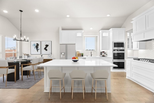 kitchen with a center island, white cabinets, vaulted ceiling, and appliances with stainless steel finishes