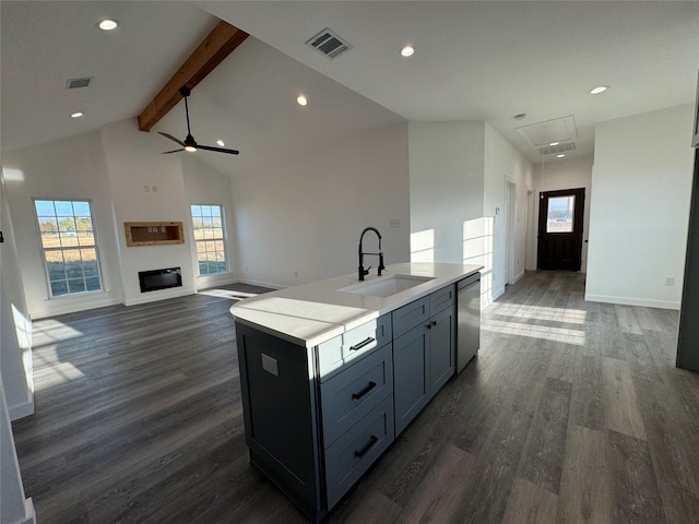 kitchen featuring dishwasher, dark wood-type flooring, a center island with sink, sink, and beam ceiling