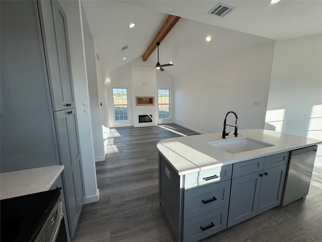 kitchen featuring ceiling fan, sink, a center island with sink, dishwasher, and vaulted ceiling with beams