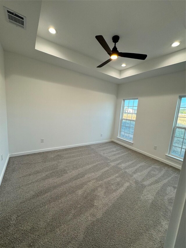 empty room featuring carpet flooring, ceiling fan, and a tray ceiling